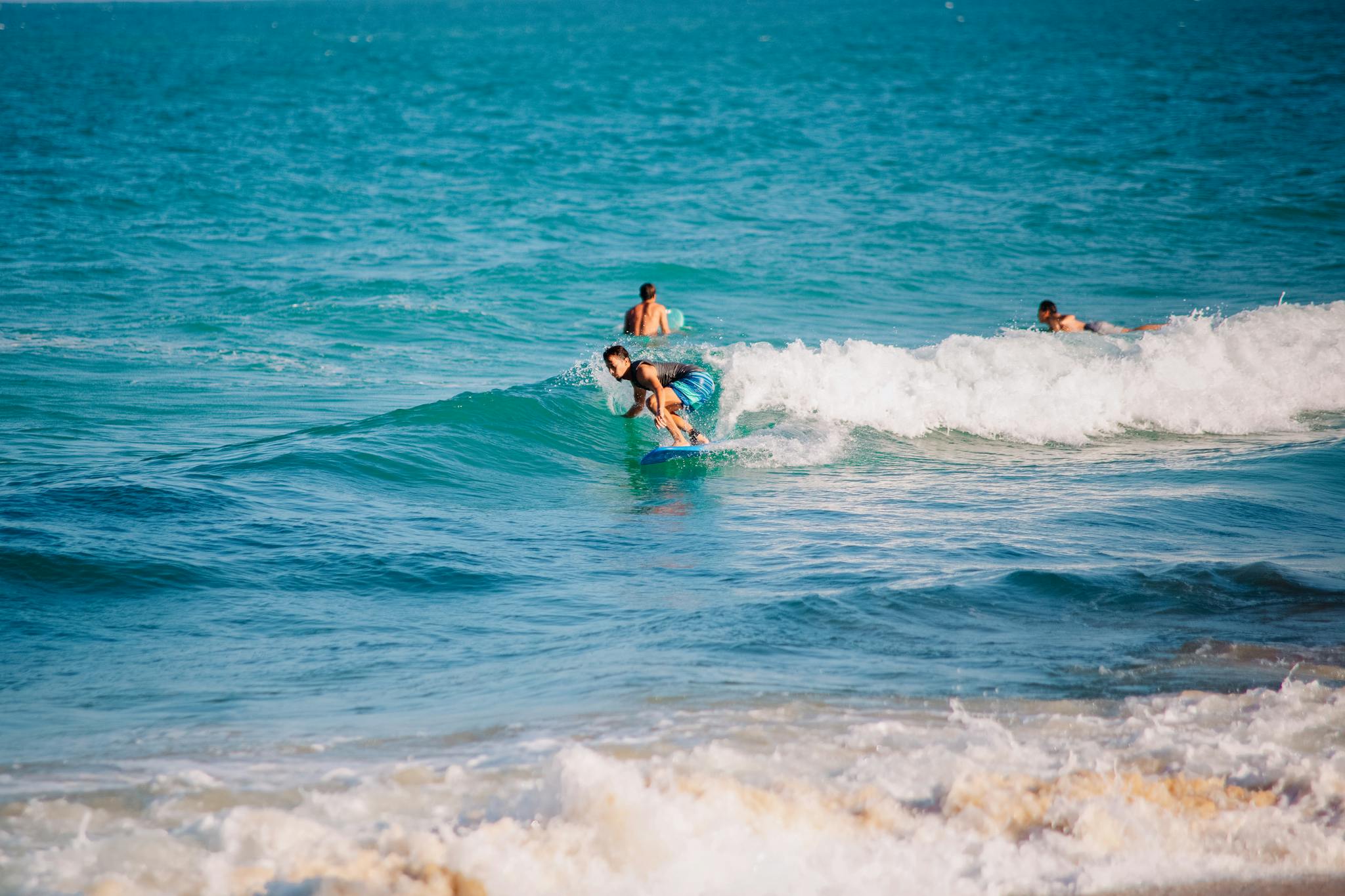 Group of surfers catching waves at a scenic beach under the bright sun.